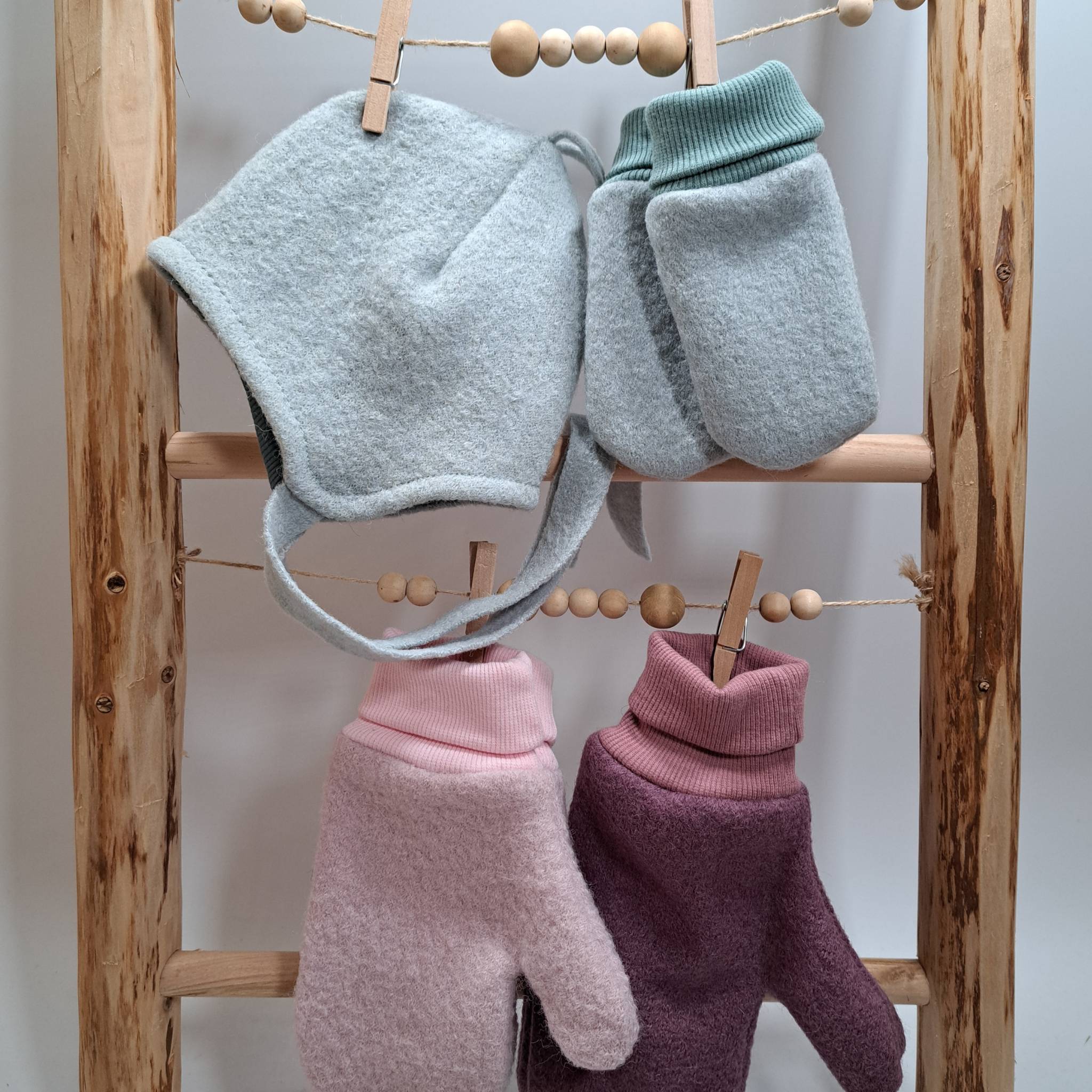 Wollwalkaccessoires für Babys und Kinder. Hier eine Bindemütze mit passenden Fäustlingen in mint und Handschuhe in rosa und beere.