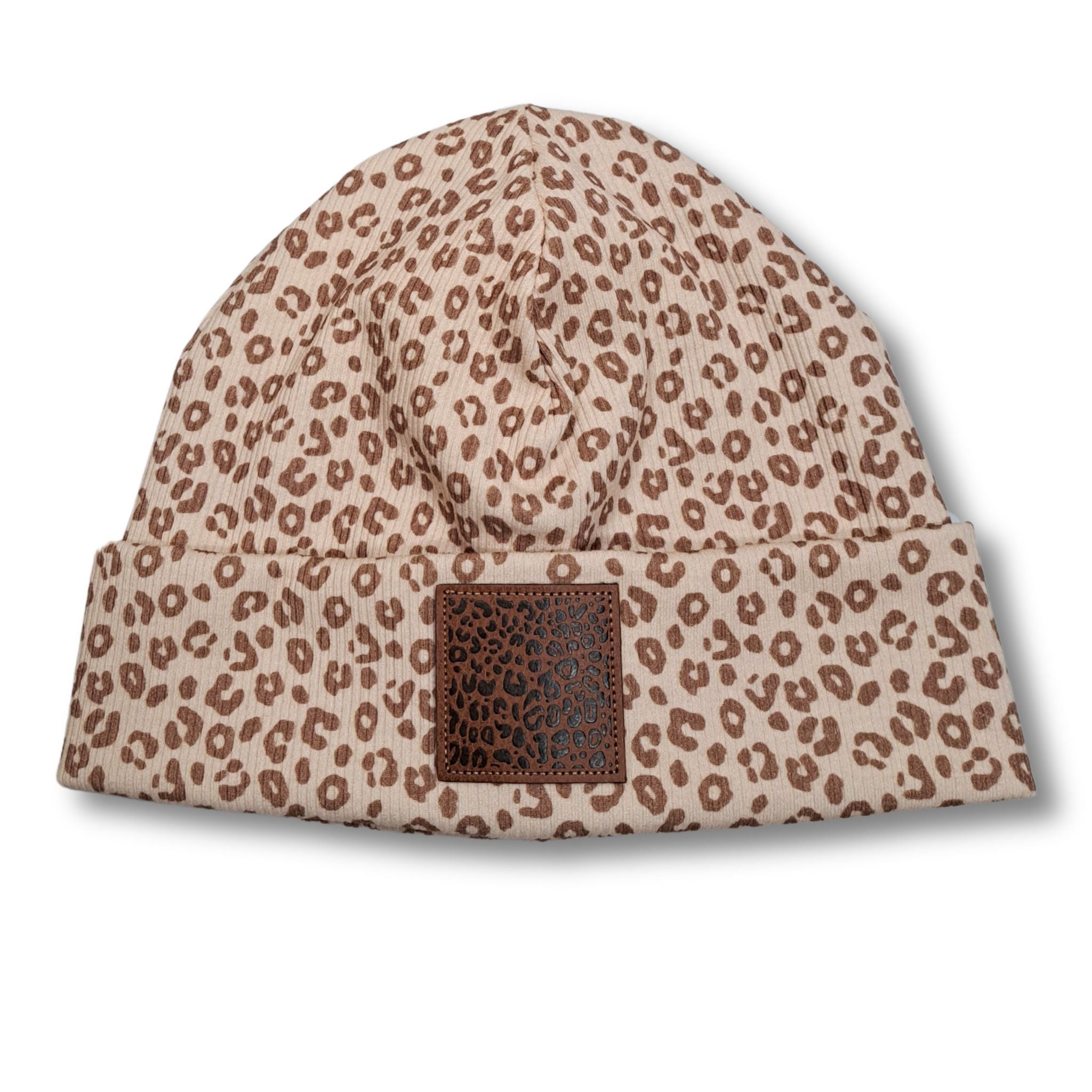 Mütze "Leo" aus beigefarbenem Rib-Jersey und braunem Leo-Print. Auf dem Umschlag befindet sich ein brauner Kunstleder-Patch mit schwarzem Leo-Print.